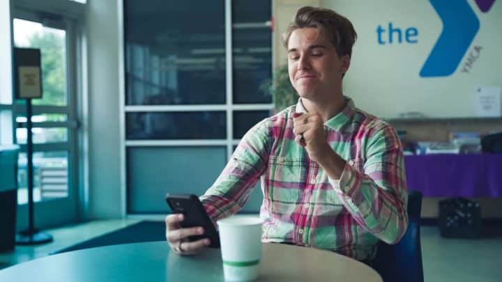 YMCA employee man playing attenski on his phone