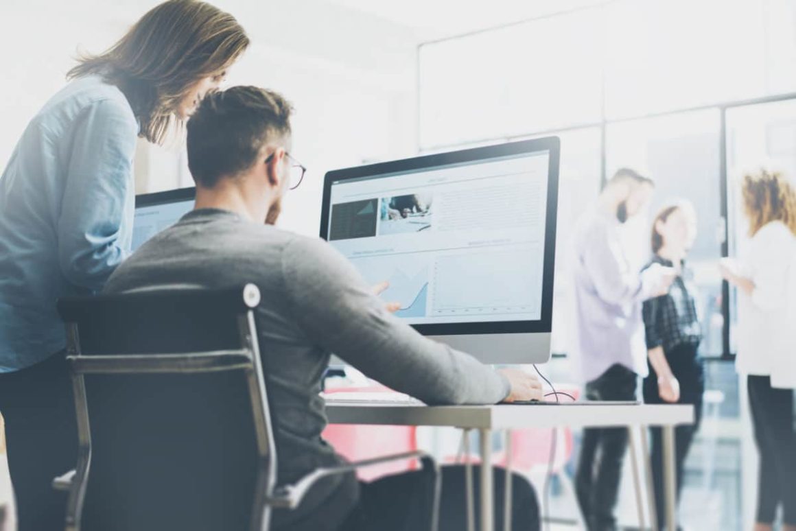 Two people looking at a desktop computer